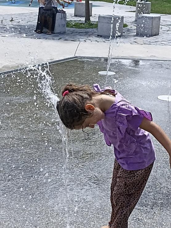 Niña jugando con agua de la plaza 