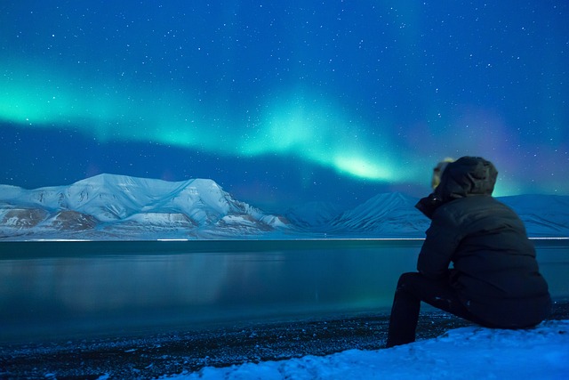 Hombre mirando el cielo en un paisaje de nieve con aurora boreal
