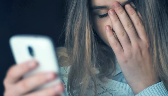 Mujer mirando celular con preocupación y angustia