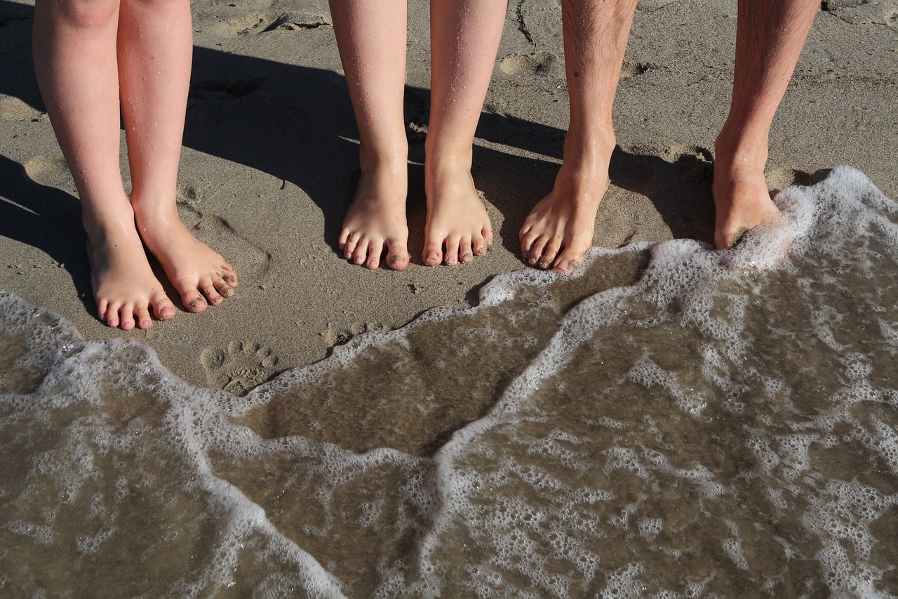 Piernas y pies de niños en la orilla del mar