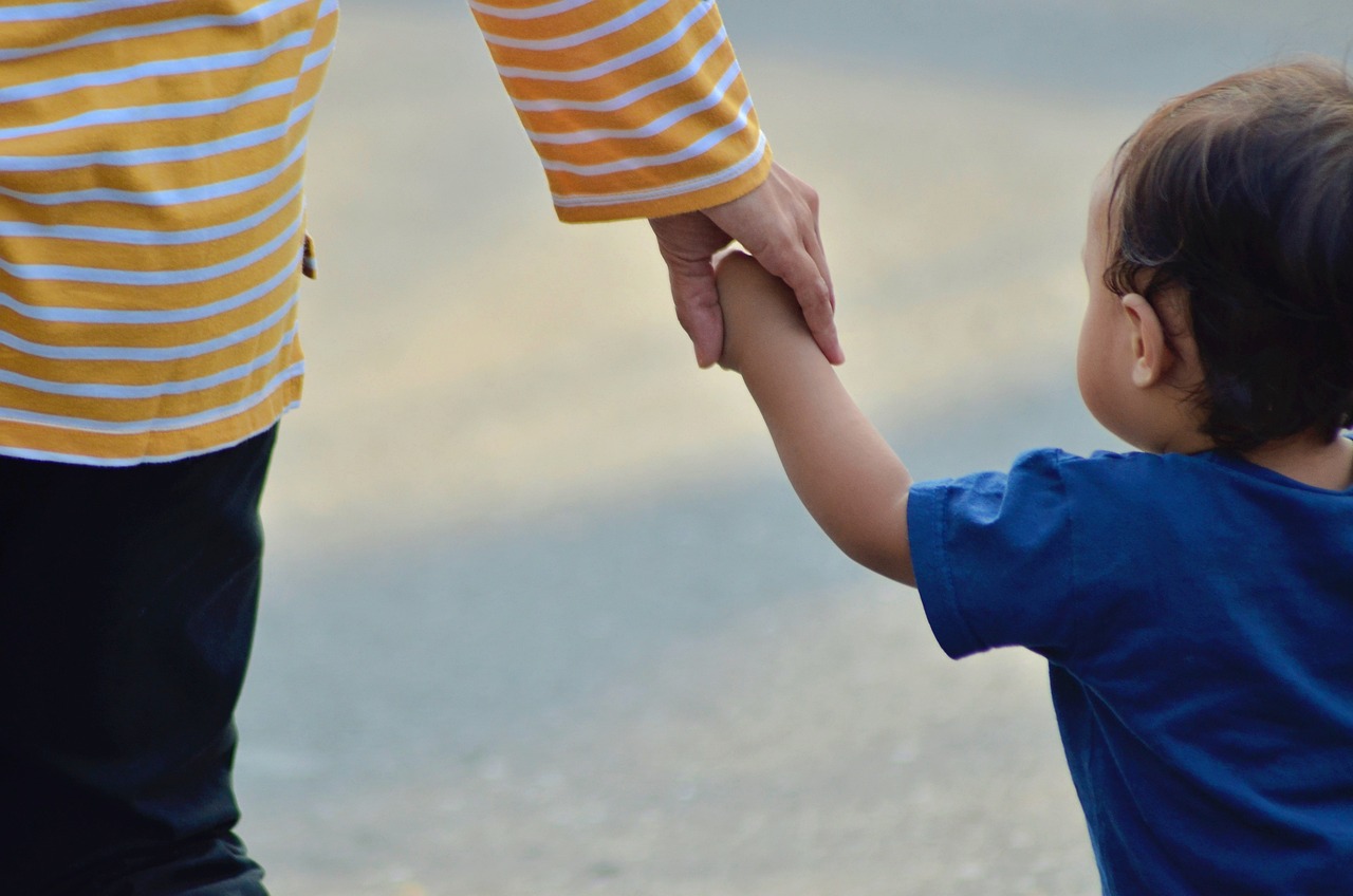 Niño tomado de la mano de adulto