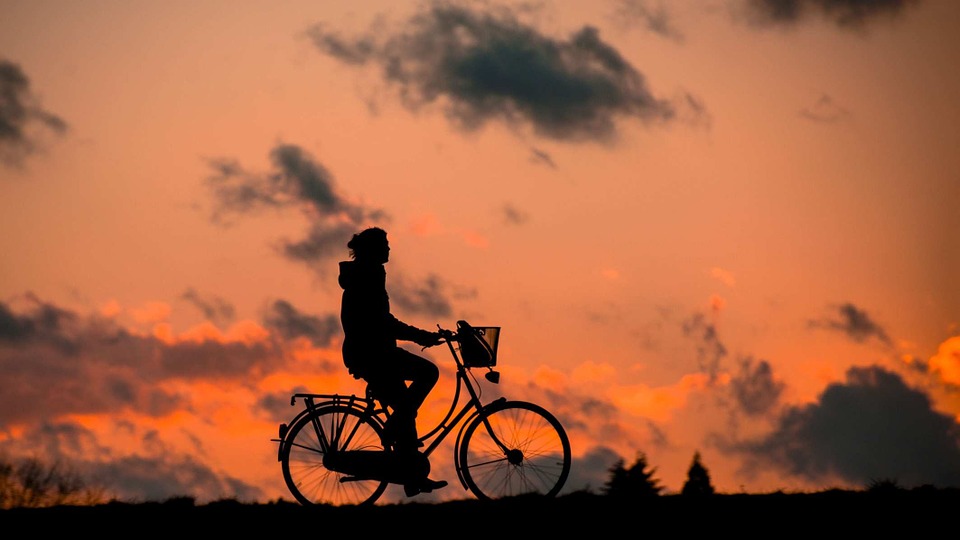 Mujer andando en bicicleta al atardecer