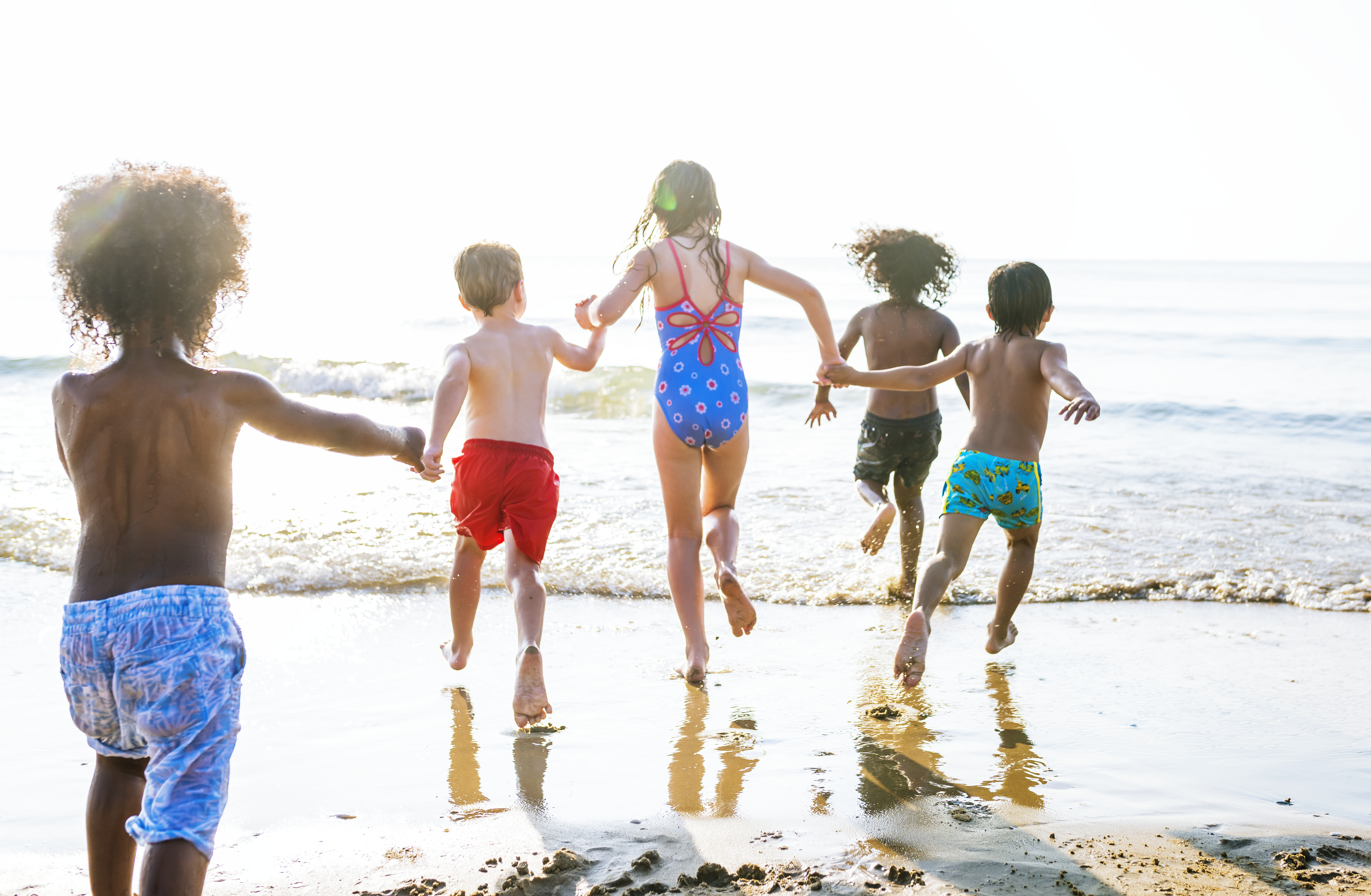 Fotografía de niños en la playa, a orillas del agua.