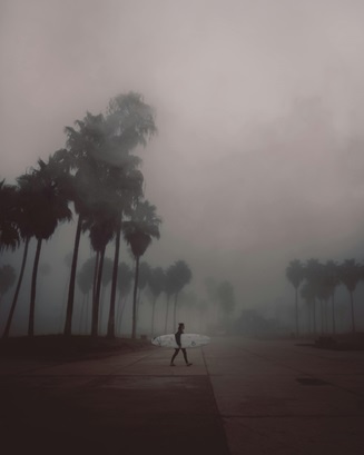 Surfista caminado en una calle llena de smog