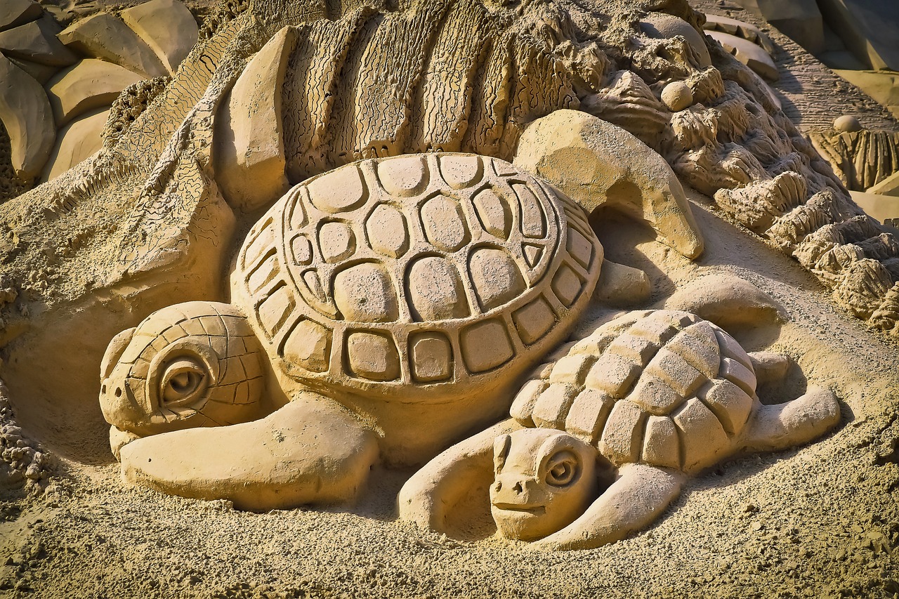 Escultura de tortugas realizada en arena en una playa 
