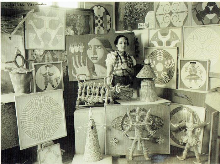Fotografía de una mujer que está rodeada de obras pictóricas